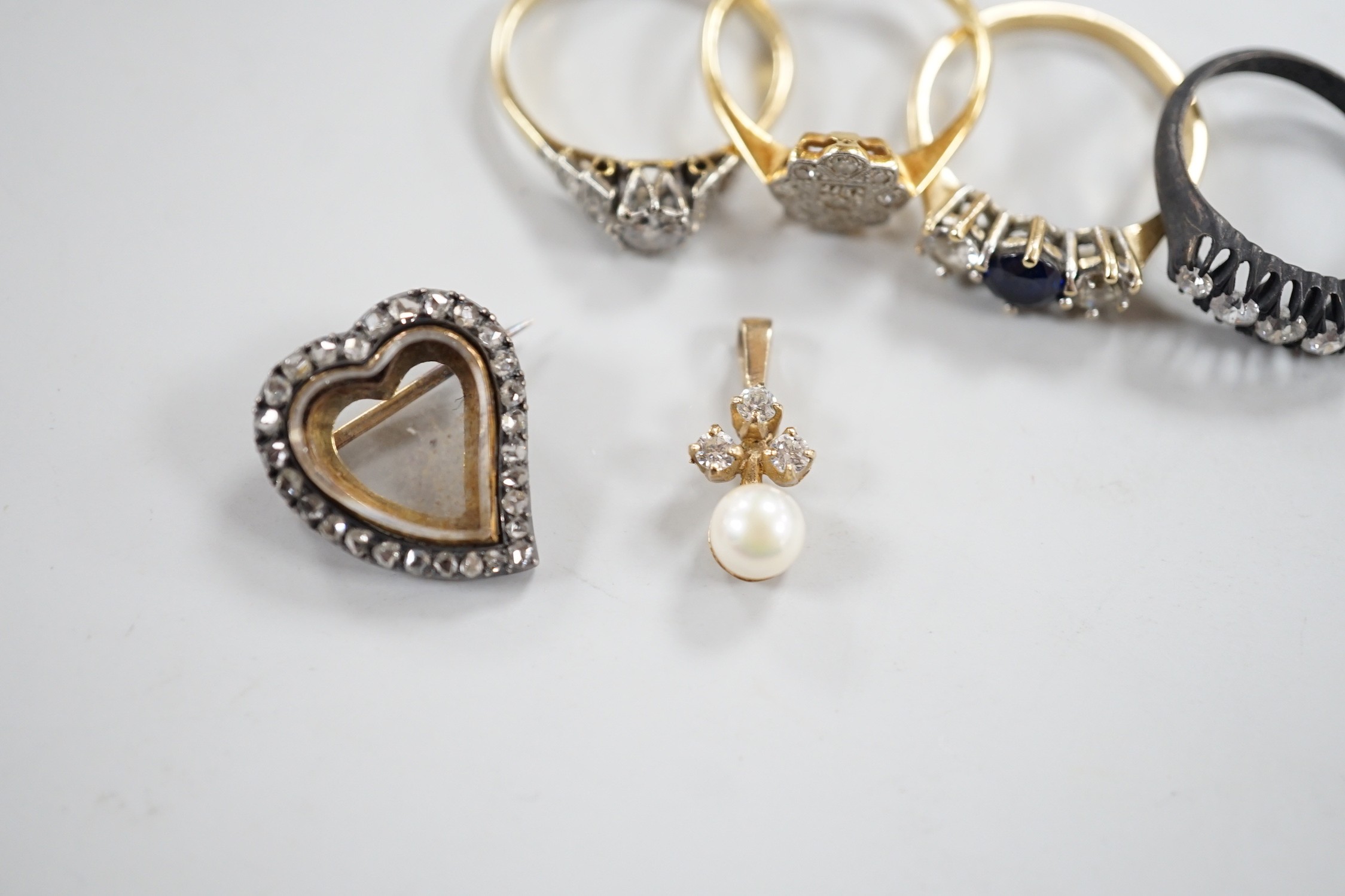 An 18ct, plat and single stone diamond ring, with diamond set shoulders, size O, a similar diamond cluster ring, size N, a blackened? 18ct gold and five stone diamond ring, a late Victorian diamond set heart shaped mourn